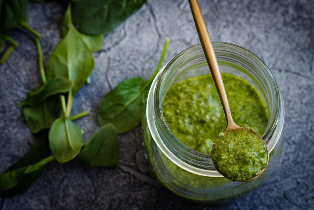 Bowl of fresh pesto with a spoon relating to an outdoor picnic and wine pairing menu.